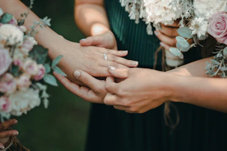 A romantic scene of a couple holding hands surrounded by soft pink and gold wedding decor.