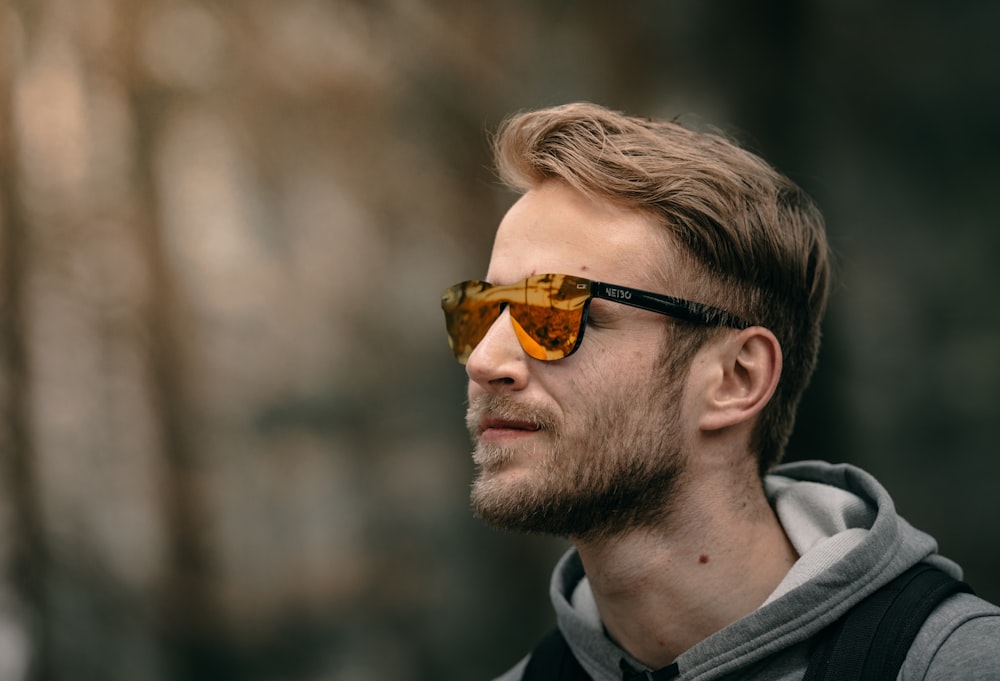 a man wearing sunglasses and a hoodie looks off into the distance