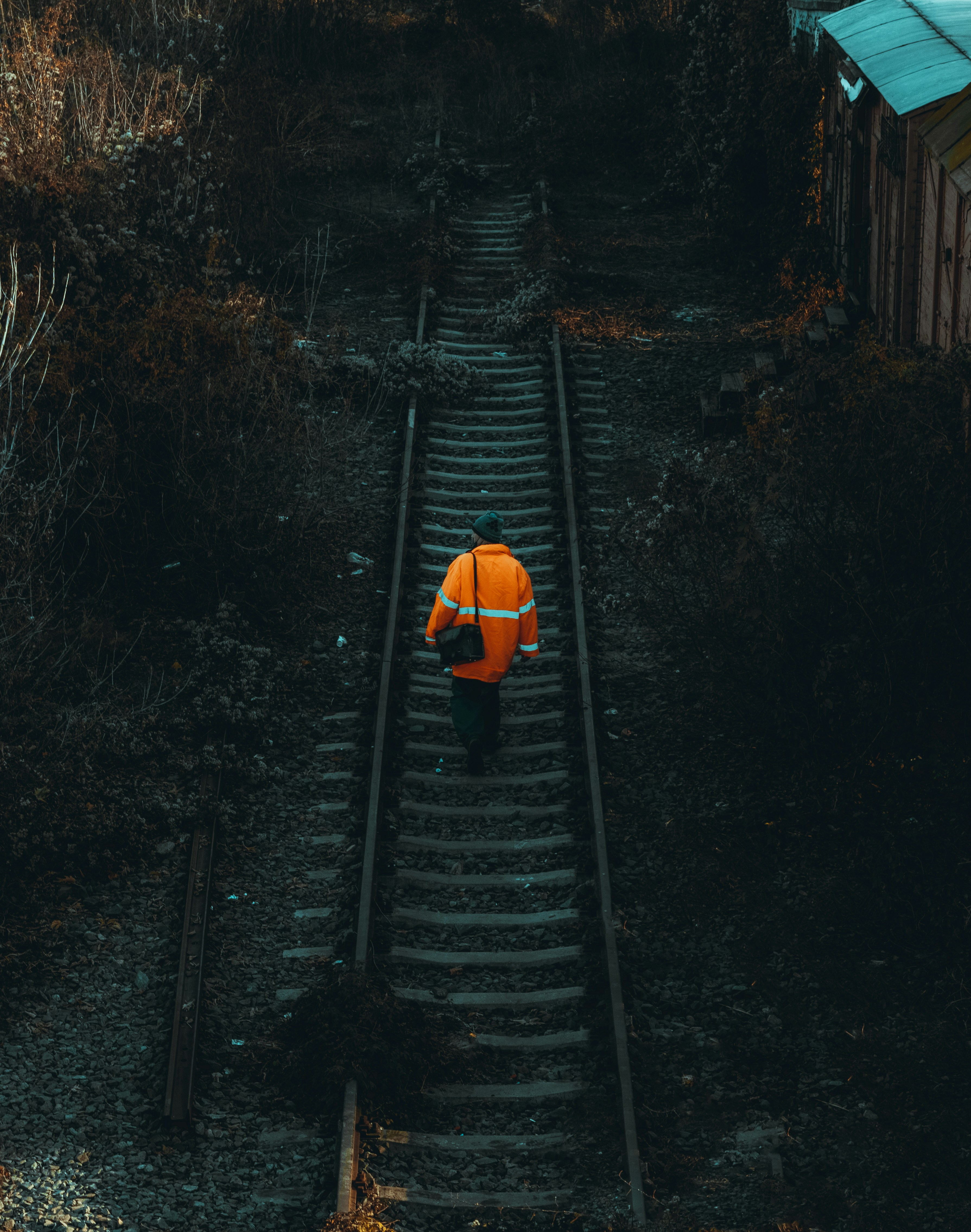a person in an orange jacket walking down train tracks