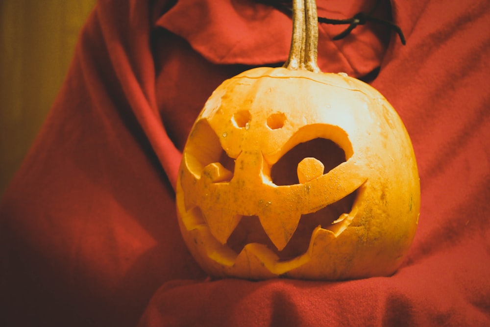 a carved pumpkin sitting on top of a red cloth