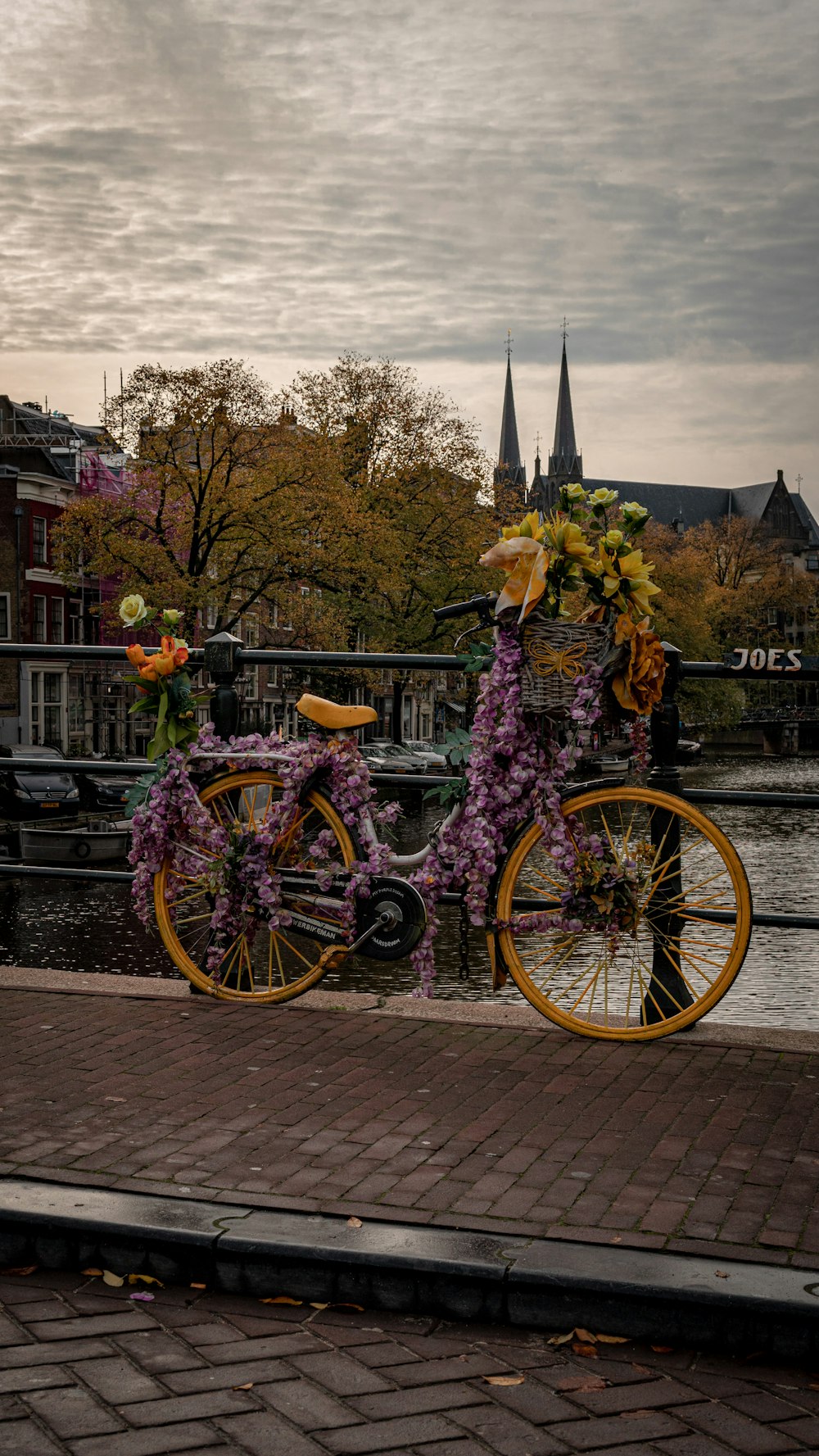 a yellow bicycle with flowers on it parked next to a river