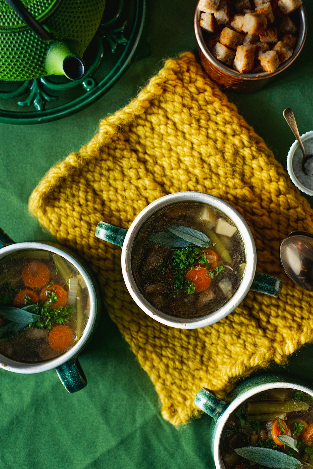 a table topped with three bowls of soup