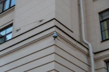 CCTV camera positioned on a building corner overlooking a busy street.