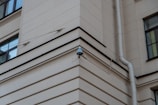 A security camera mounted on a building watching over a street.