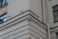 Close-up of a CCTV camera mounted on a building corner.