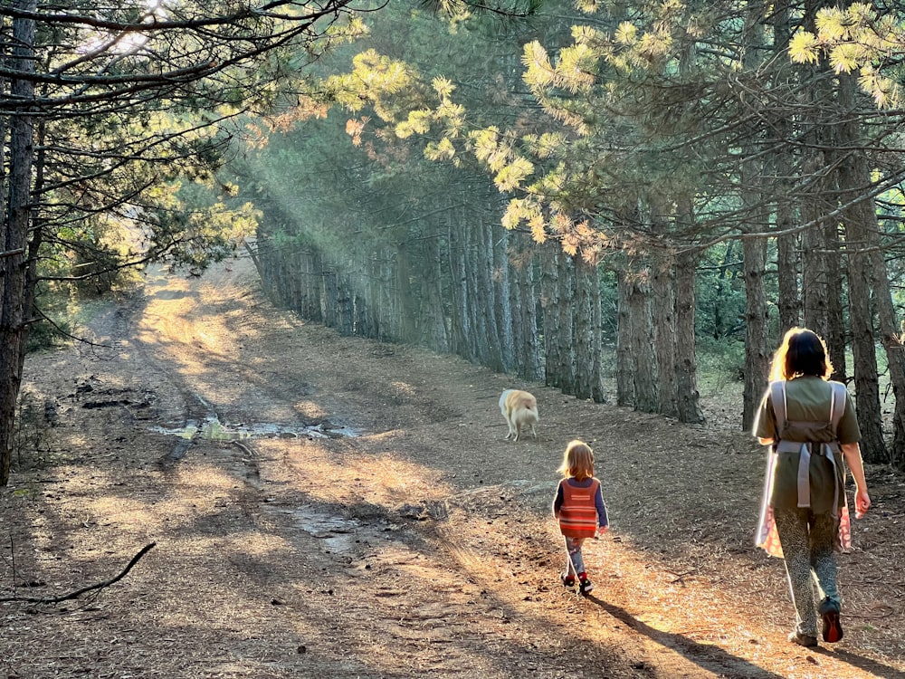 a woman and a child are walking in the woods