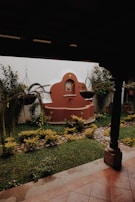 A peaceful corner with a small fountain surrounded by potted medicinal herbs.