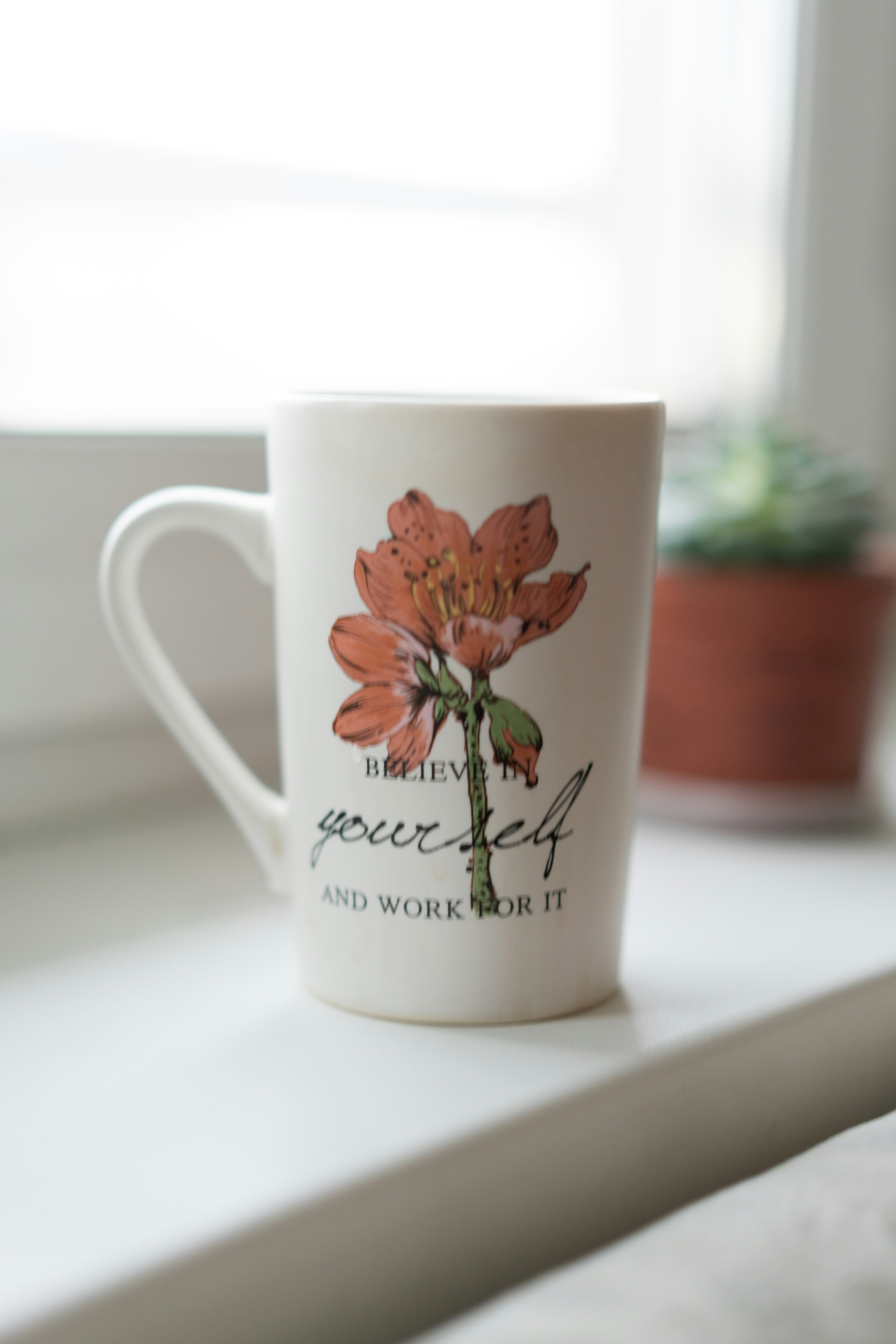 a coffee cup sitting on top of a window sill