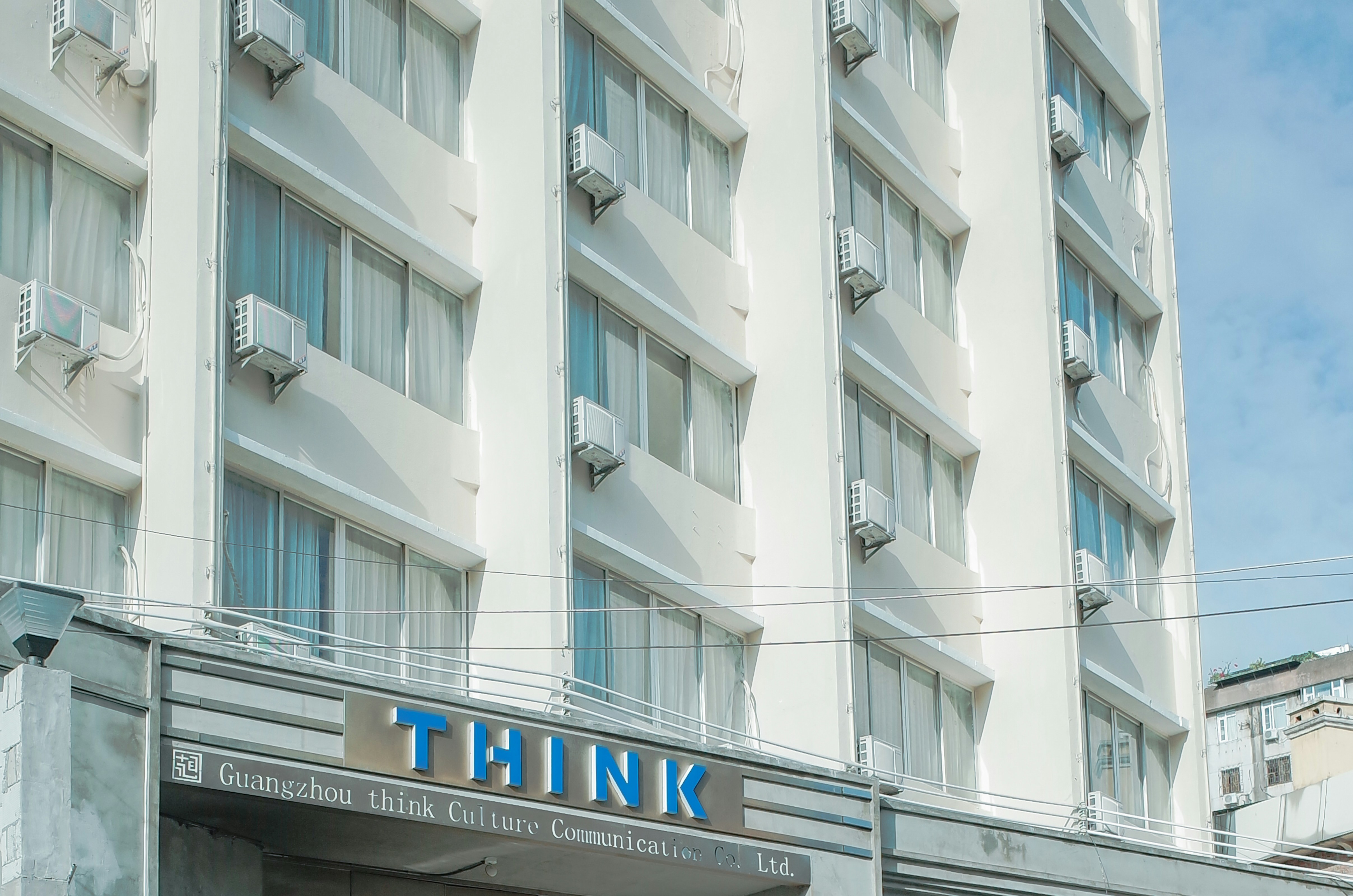a tall white building with a sign that says think