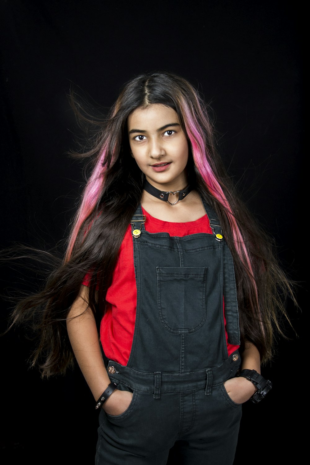 a girl with pink hair and black overalls