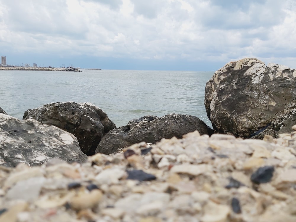 a rocky beach with a body of water in the background