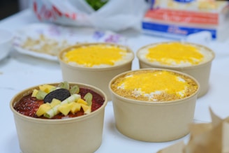 a table topped with three cups filled with food