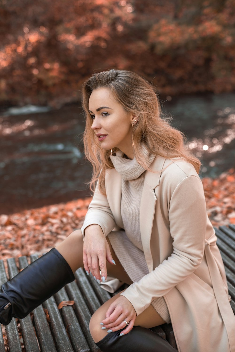 a woman sitting on top of a bench next to a river