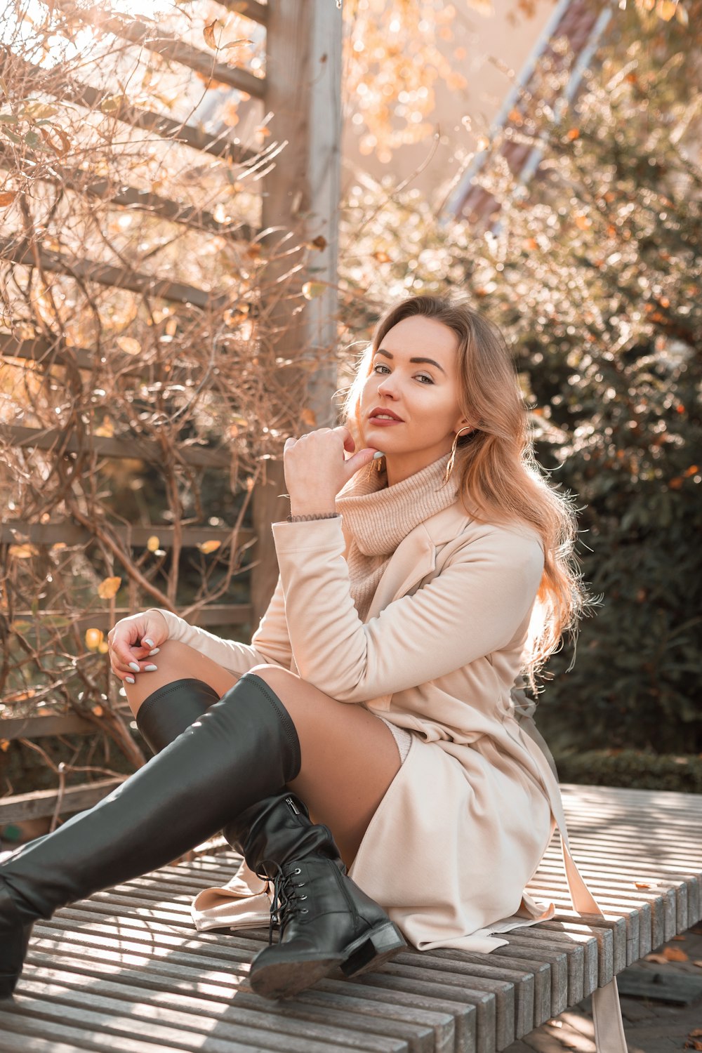 a woman sitting on a wooden bench wearing boots