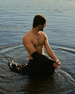 a shirtless man sitting in a body of water