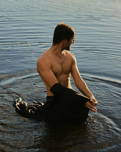 a shirtless man sitting in a body of water
