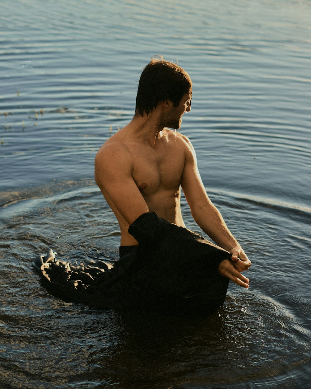 a shirtless man sitting in a body of water