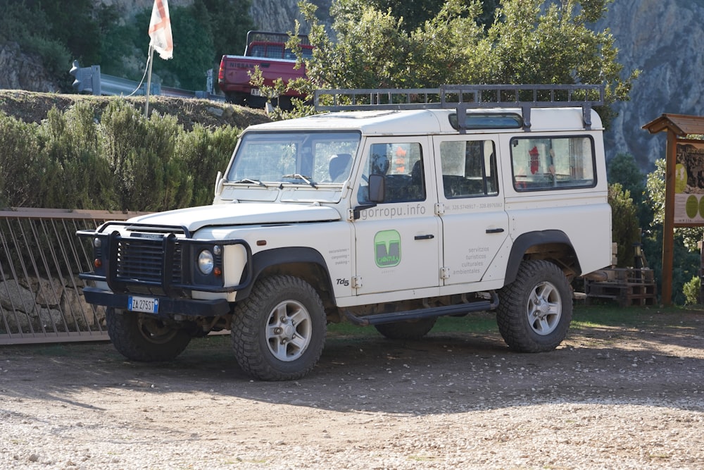 a white land rover parked in front of a fence