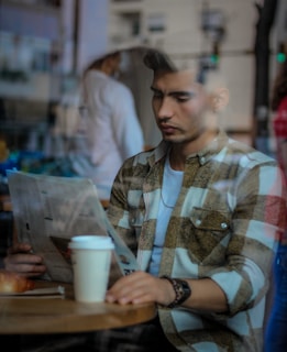 Close-up of a newspaper being read in a bustling café.