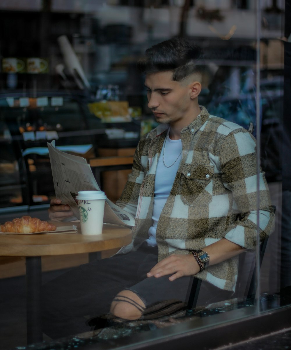 a man sitting at a table looking at a laptop