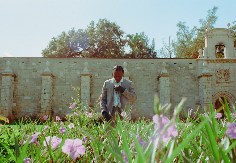 a man in a suit standing in a field of flowers