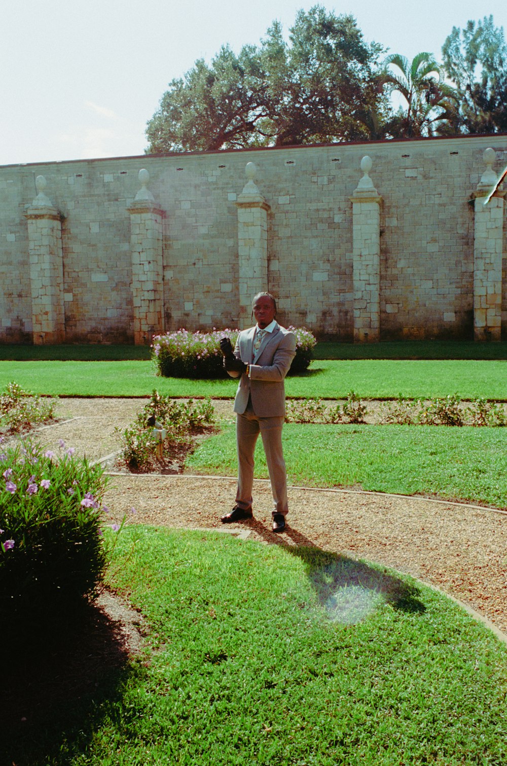 a man in a suit standing in a garden