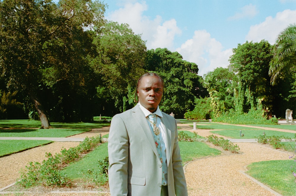 a man in a suit standing in a garden