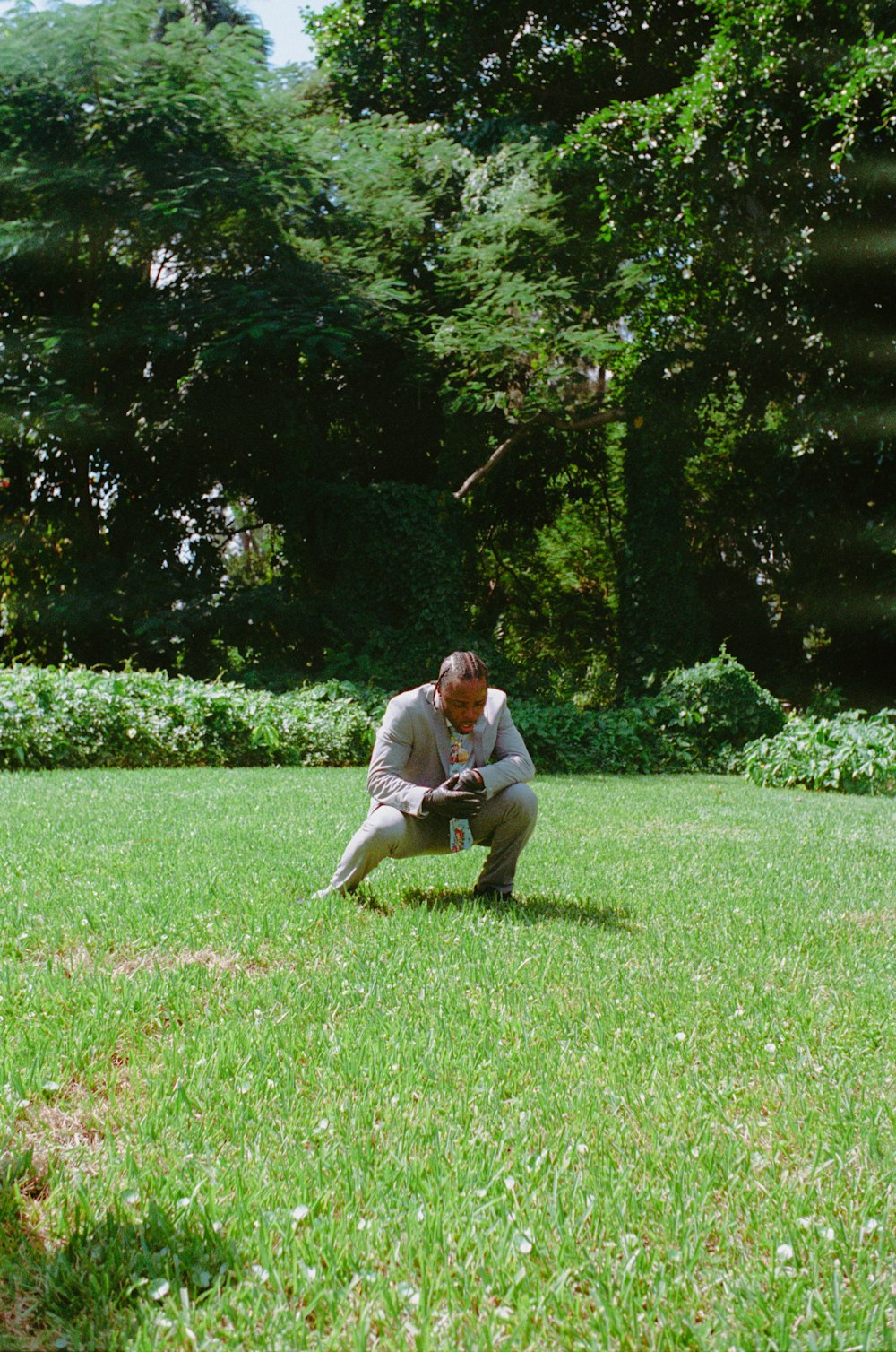 풀밭에 무릎을 꿇고 카메라를 들고 있는 남자