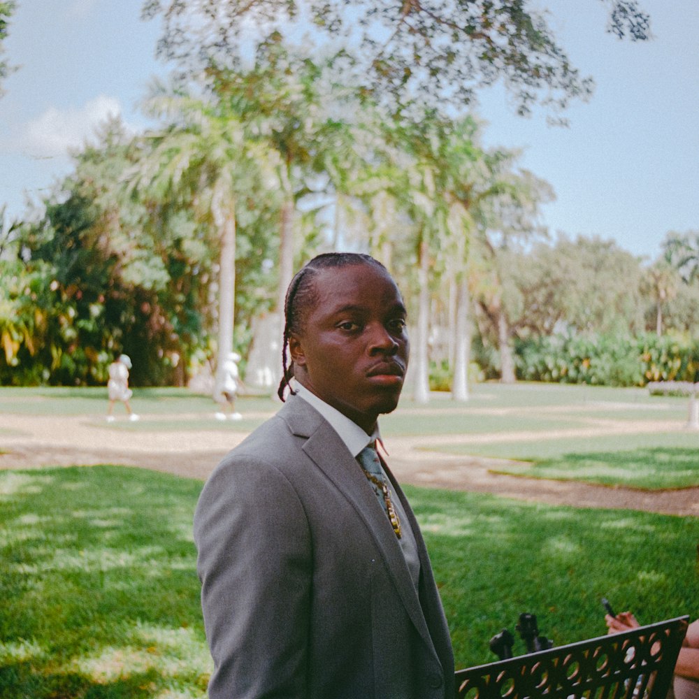 a man in a suit and tie standing in a park