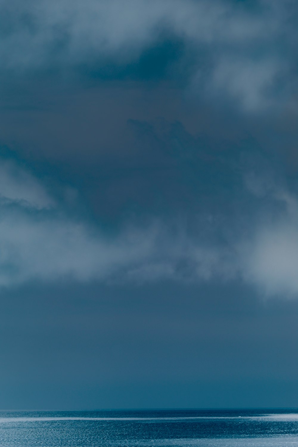 a lone boat on the ocean under a cloudy sky