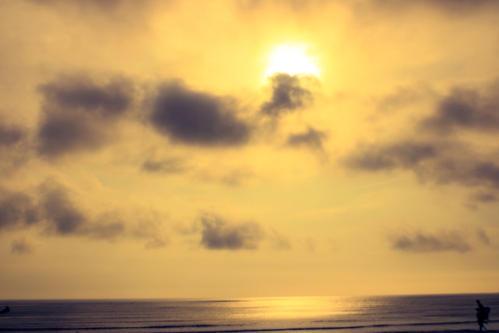 a couple of people standing on top of a beach under a cloudy sky