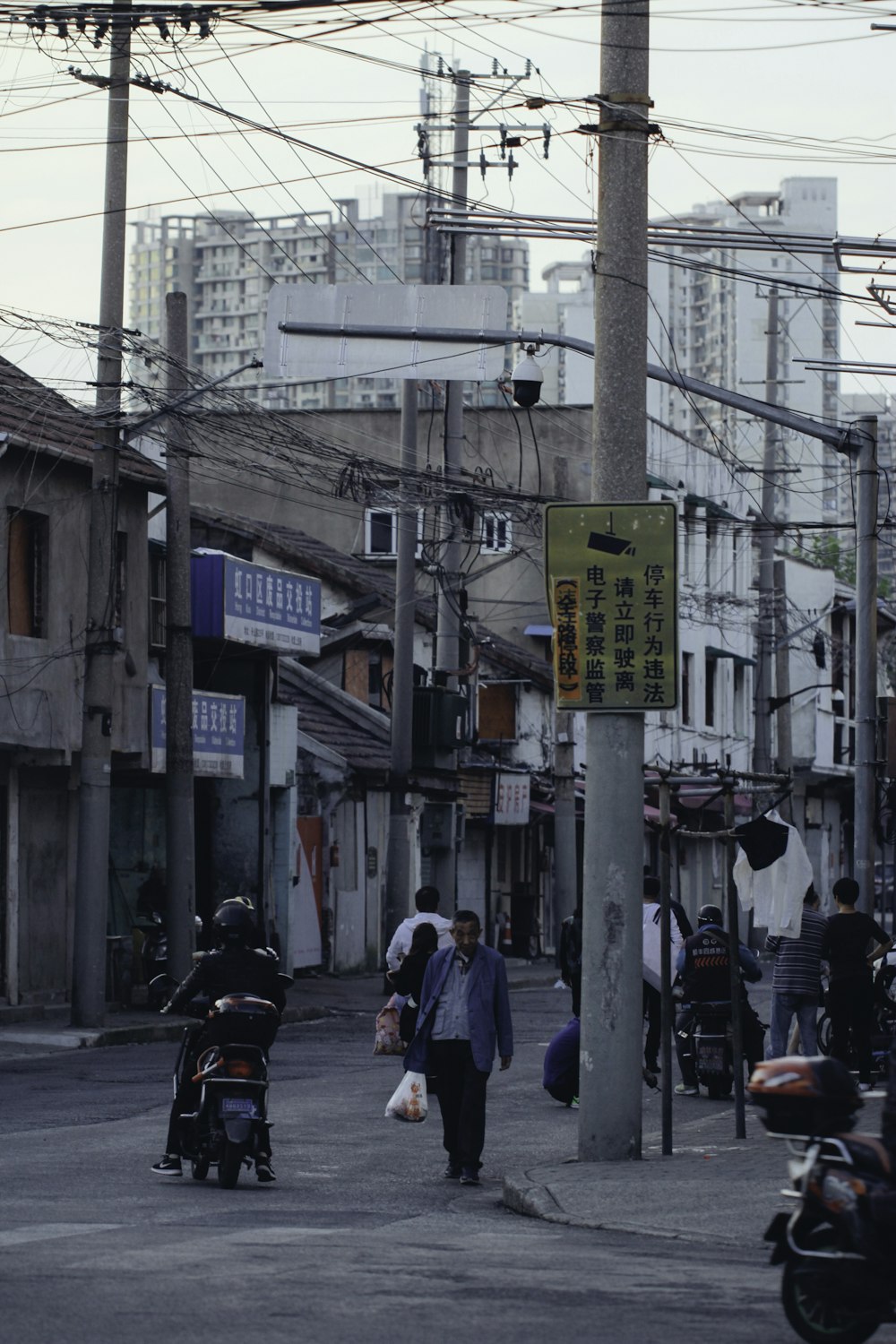 a group of people walking down a street next to tall buildings