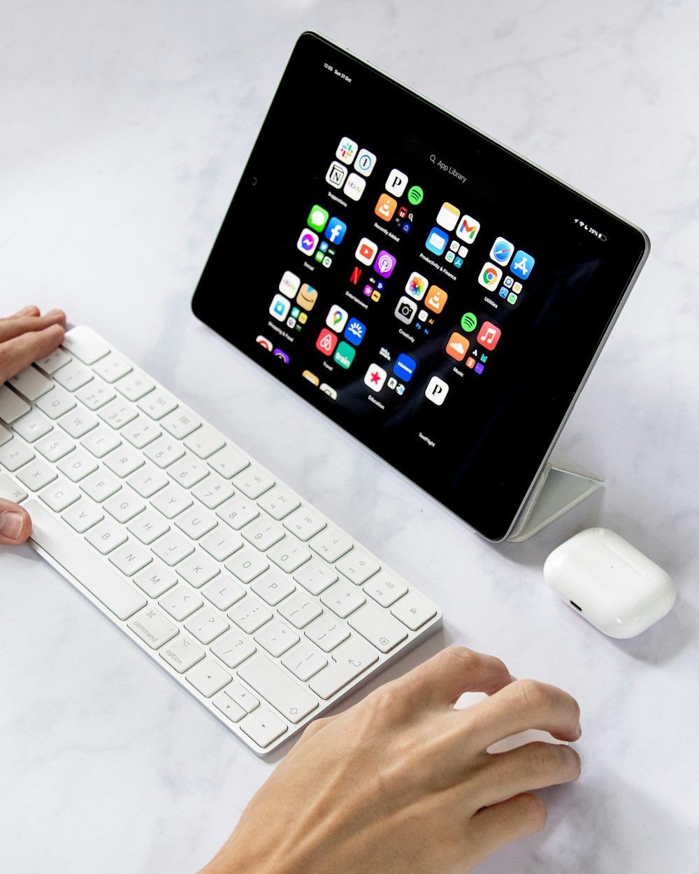 a person typing on a keyboard next to a tablet