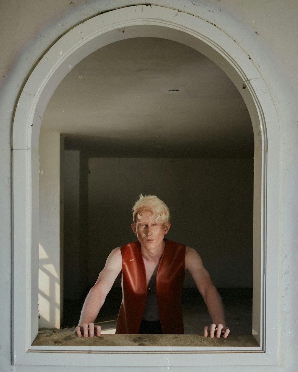 a woman in a red vest looking out of a window
