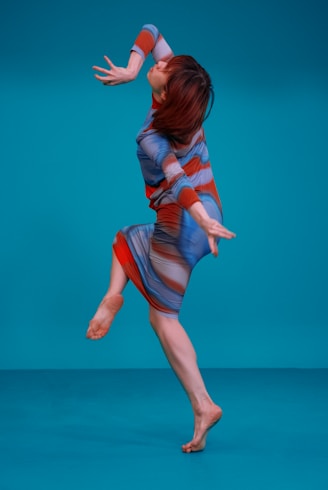 a woman jumping in the air while wearing a dress