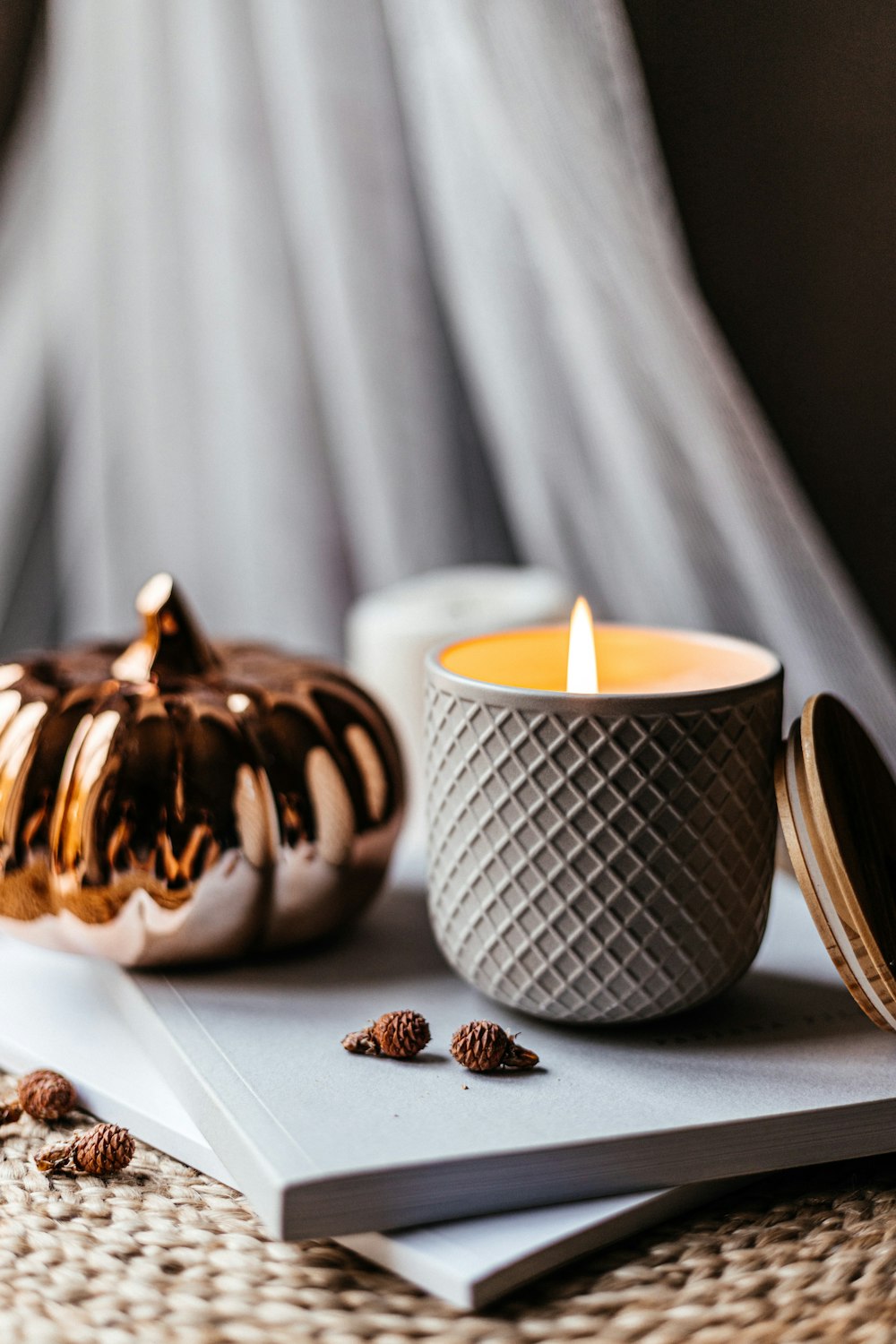 a candle sitting on top of a book next to a pumpkin