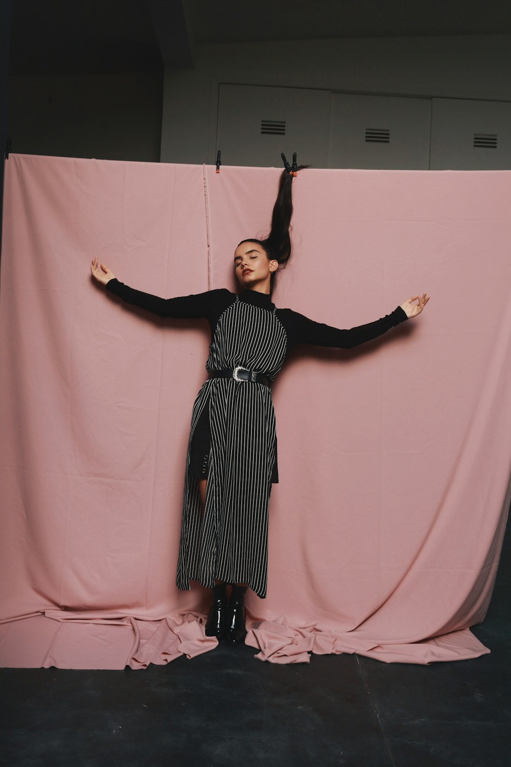 a woman standing in front of a pink backdrop