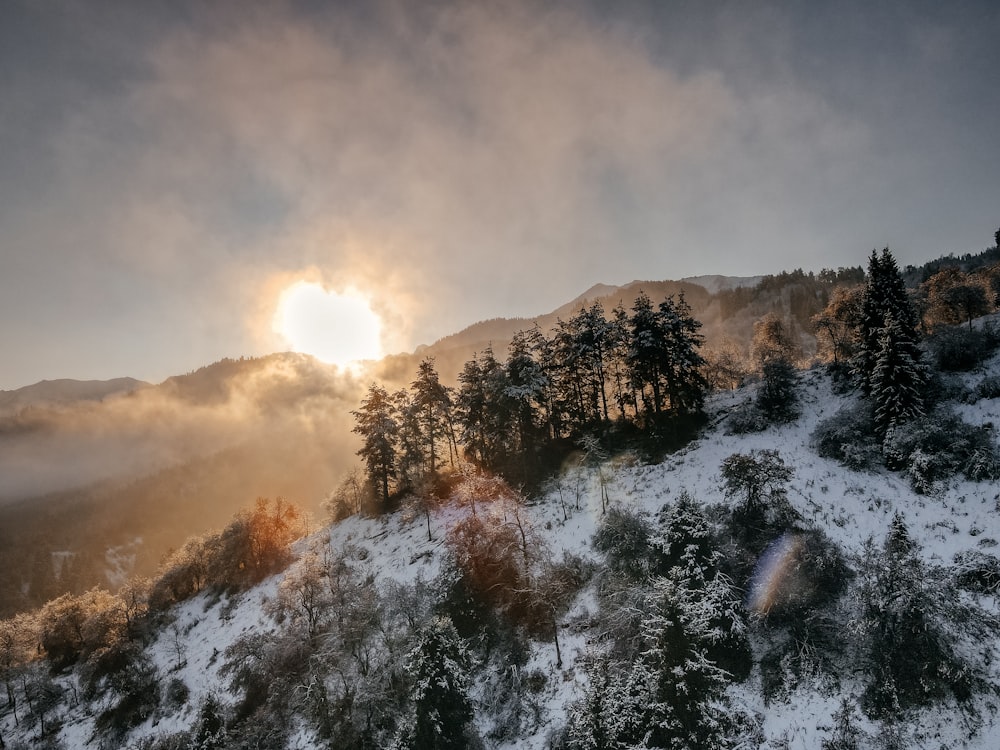 the sun shines through the clouds over a snowy mountain