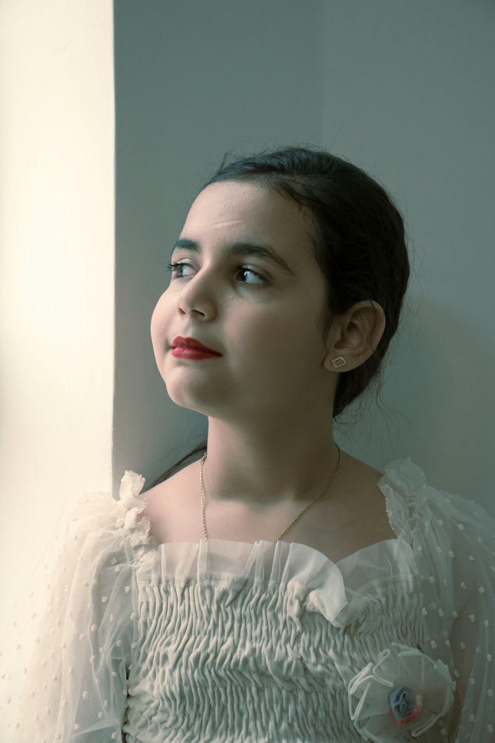 a woman in a white dress looking out a window