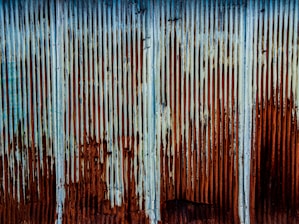 a rusted metal wall with a blue sky in the background