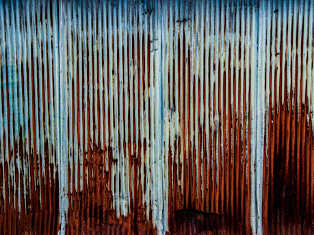 a rusted metal wall with a blue sky in the background