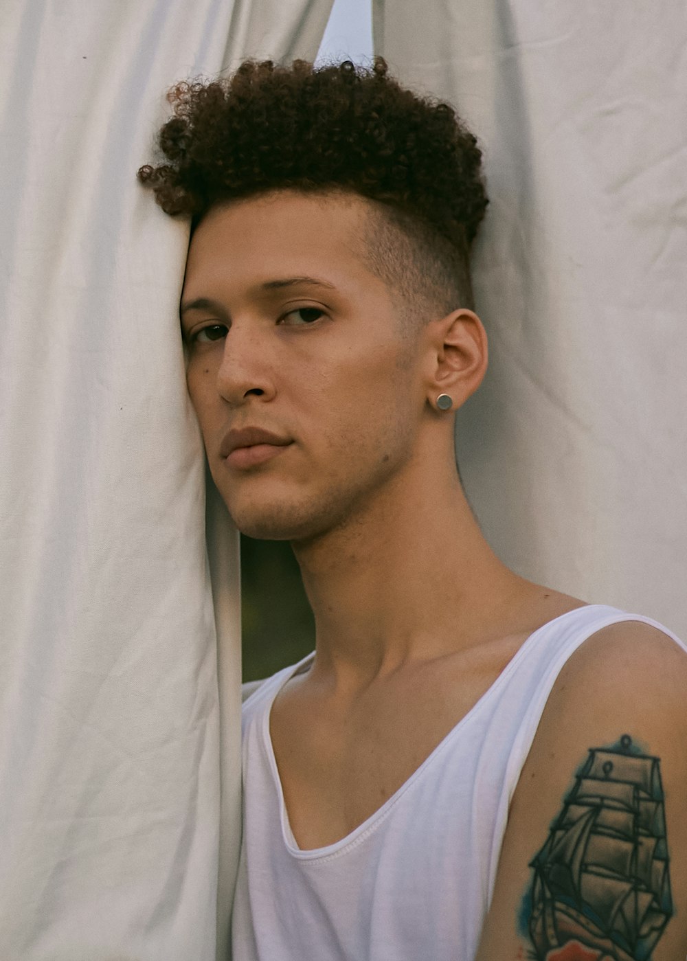 a man with a tattoo on his arm leaning against a wall