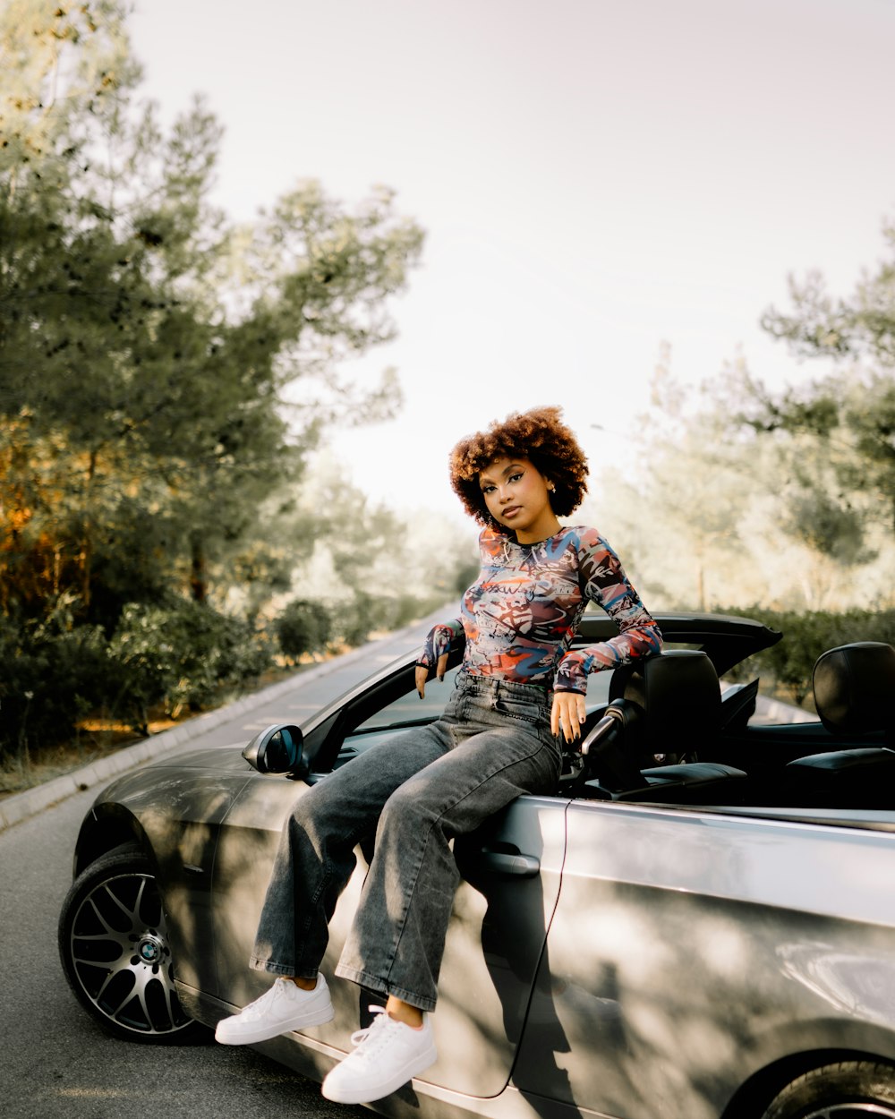 a woman sitting on the hood of a car