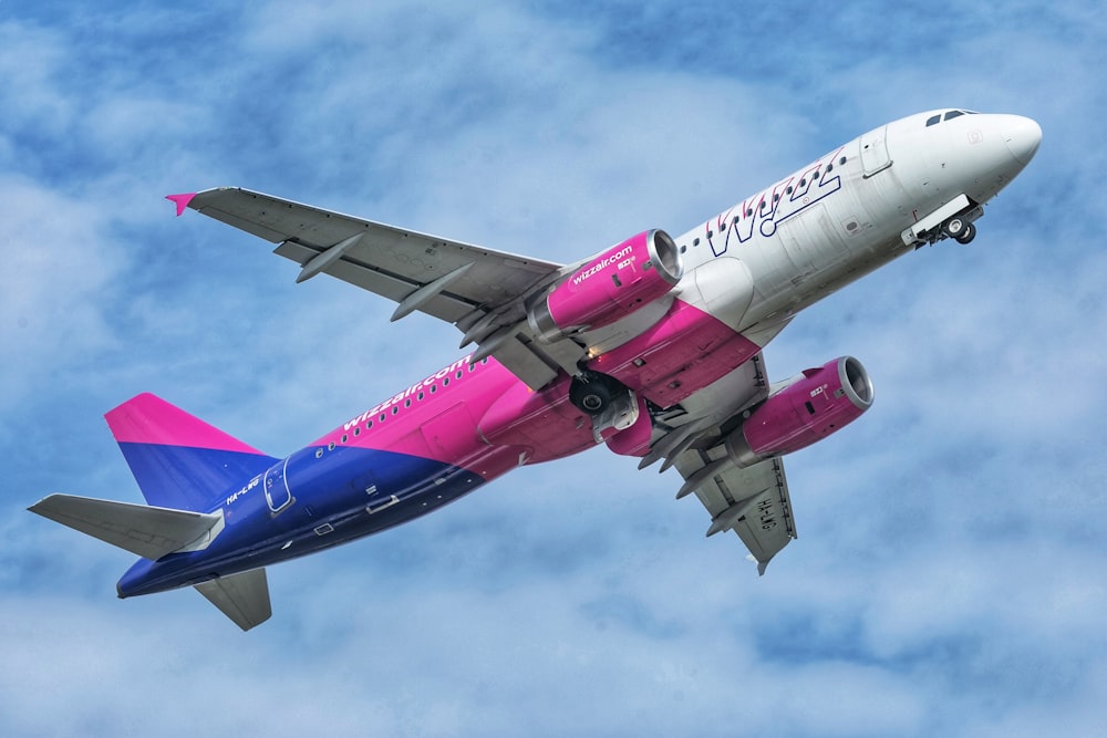 Un avión de pasajeros rosa y azul volando en el cielo