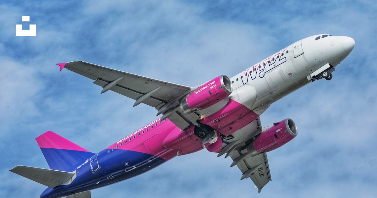 Un avion de ligne rose et bleu volant dans le ciel photo – Photo ...