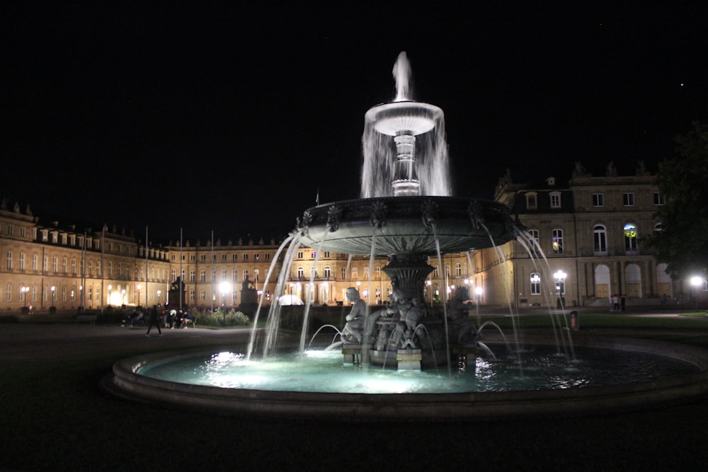 a fountain in front of a large building at night