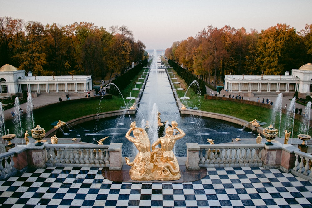 una vista di una fontana in un parco con un pavimento a scacchi