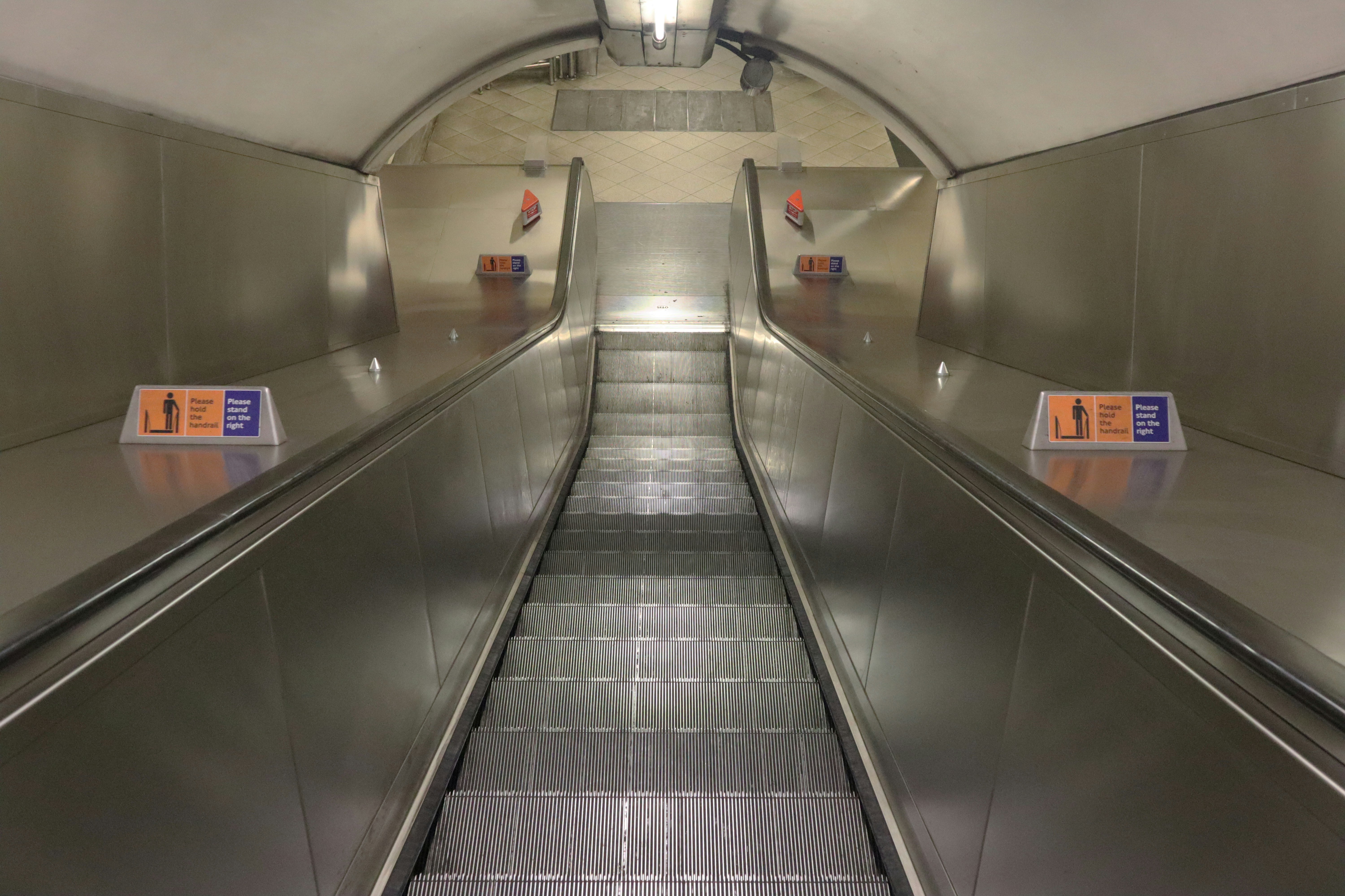 an escalator in a subway station with signs on it