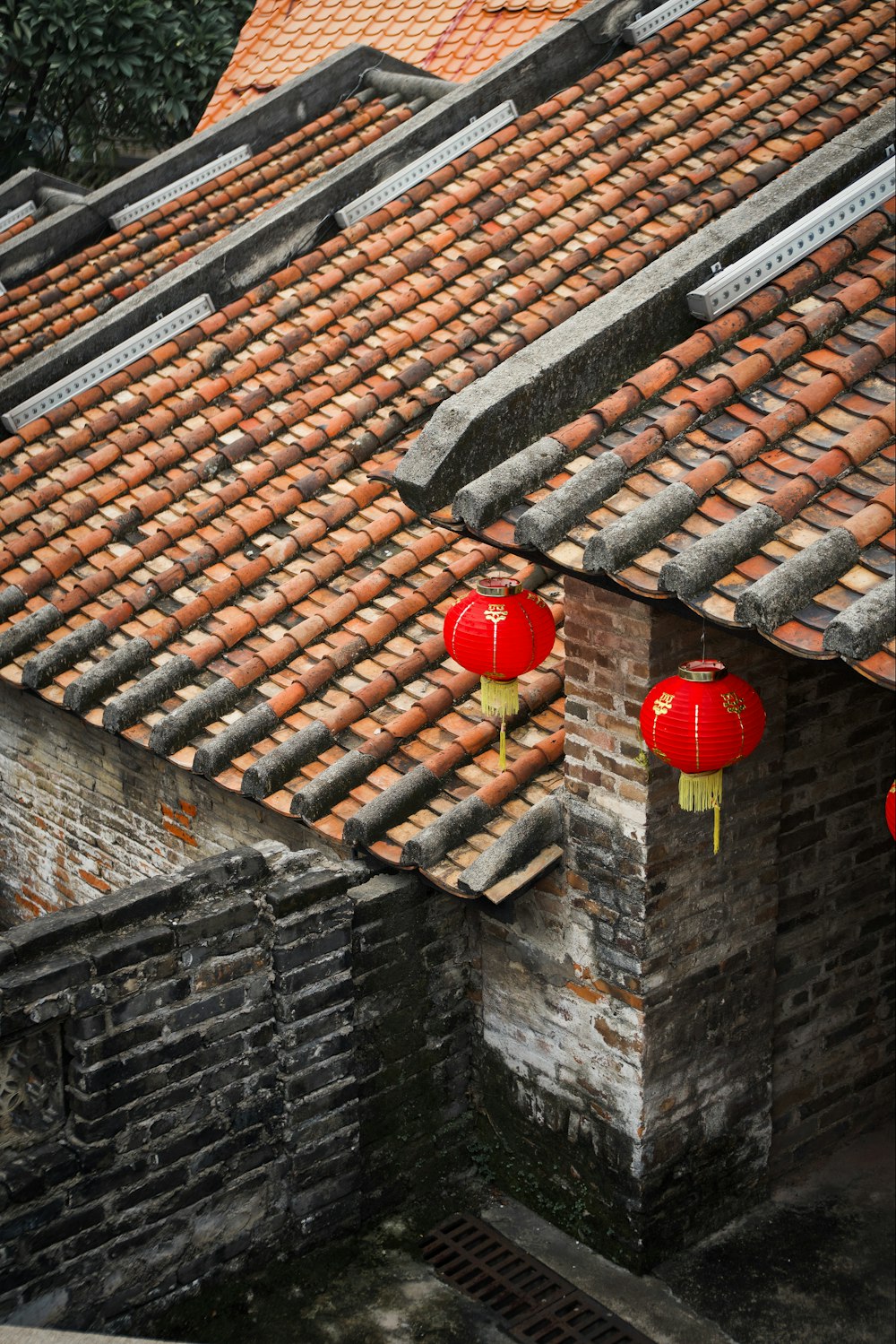 two red lanterns hanging from the roof of a building