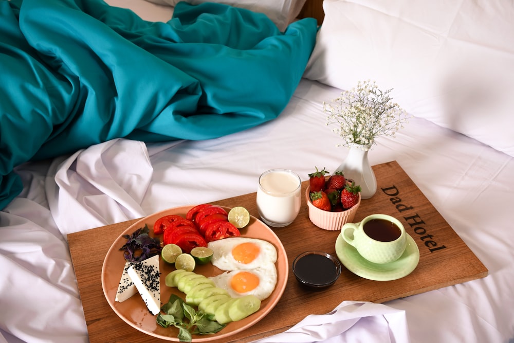 a tray of food on a bed with a cup of coffee